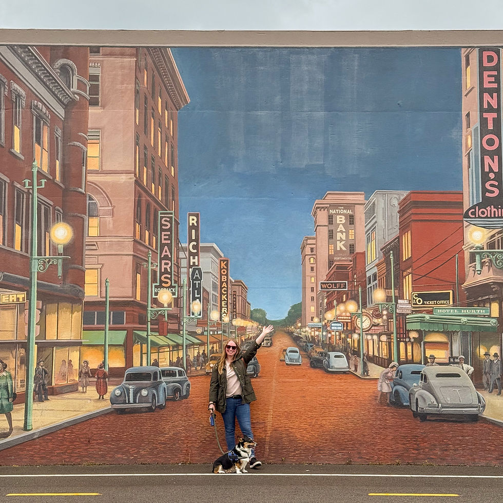 Woman with a dog poses in front of a colorful vintage city mural featuring signage like Sears and Bank. She waves, exuding a cheerful mood.
