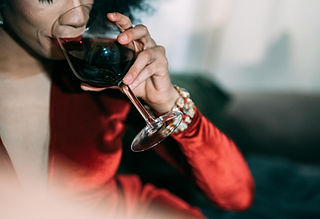 Her ses en kvinde i en rød kjole med et glas vin