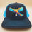 Thumbnail: Black and blue mesh hat with embroidered parrot and clock