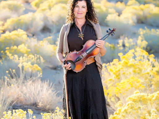 Profesora de DarKha Academy sosteniendo un violín en un entorno natural en Xàtiva, representando la conexión entre música, idiomas y aprendizaje.