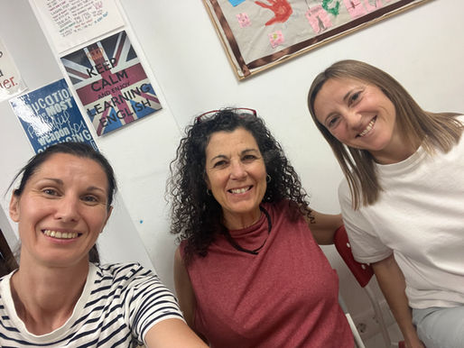 Three women participating in the DarKha Academy Bilingual Book Club in Xàtiva. The students smile while practicing English and Spanish conversation in a warm and welcoming community environment.
