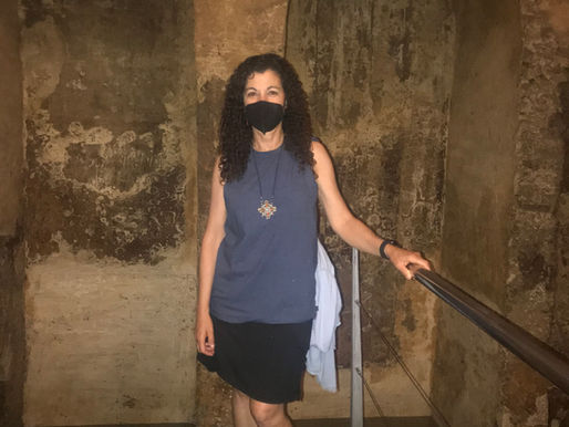 Teacher standing inside a historic stone structure with arches, representing cultural learning and exploration.