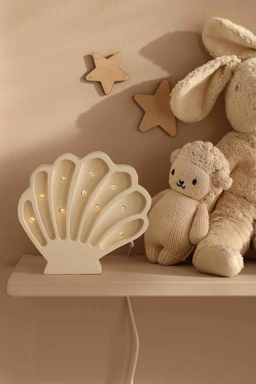Houten kinderlamp in de vorm van een witte schelp op een plank in de kinderkamer
