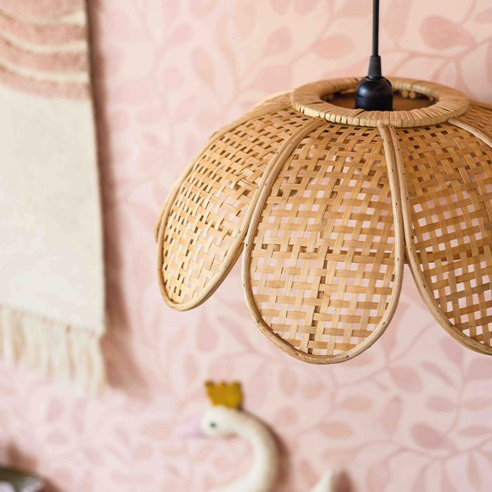 rotan hanglamp in de vorm van een bloem in een kinderkamer met roze behang