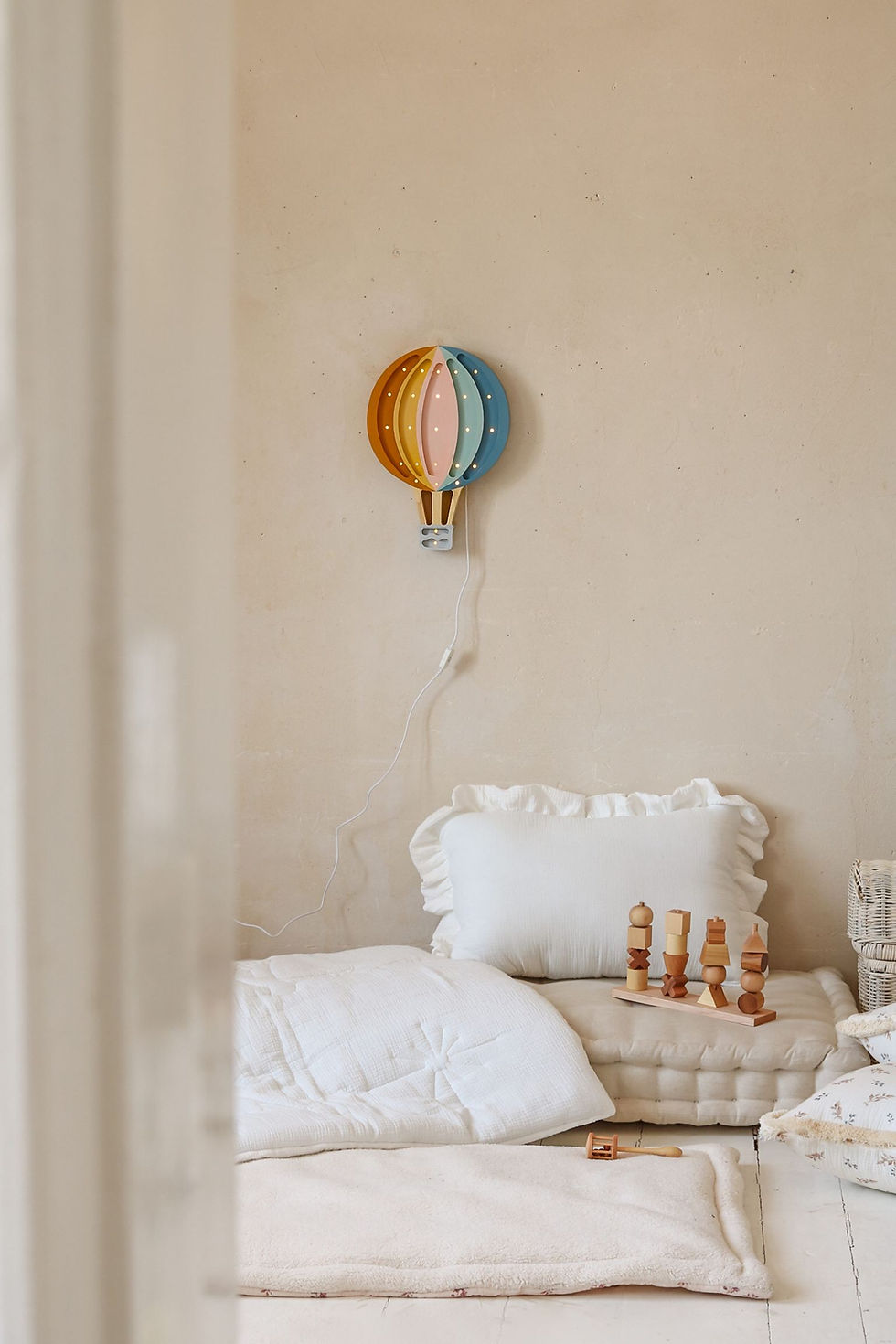 houten kinderlamp in de vorm van een luchtballon in retro kleuren in een lichte neutrale kinderkamer