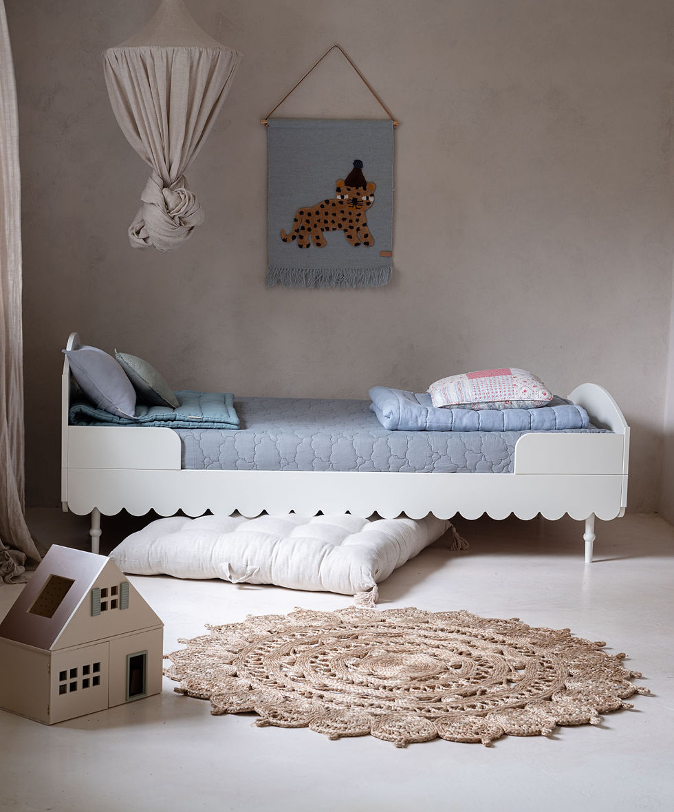 Wit kinderbed, ontworpen met decoratieve schulpenrand en sierlijke poten, in een lichte kinderkamer