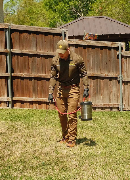 A Smile Pest Control technician treating ant mounts in a Dallas yard 