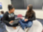 girls sitting on table with computer, laughing
