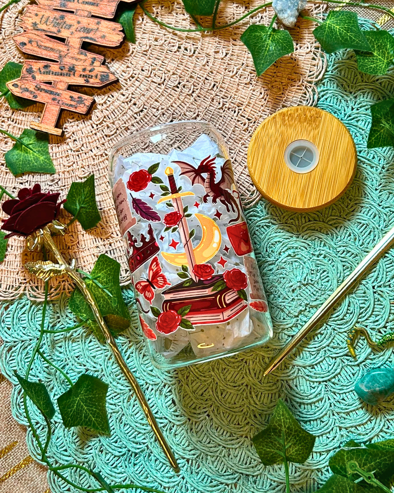 Gobelet en verre romantasy avec roses, dragon rouge et épée dans un livre.