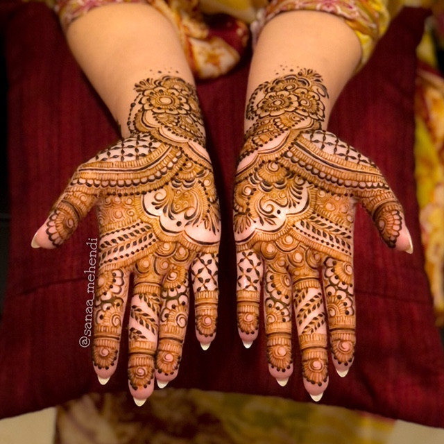 An intricate and strikingly beautiful henna design on the hands’ of a bride (up past her wrists).