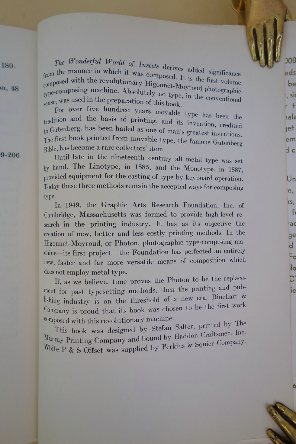 Colophon book page about printing history, with gold metal page clips at the top and bottom right.