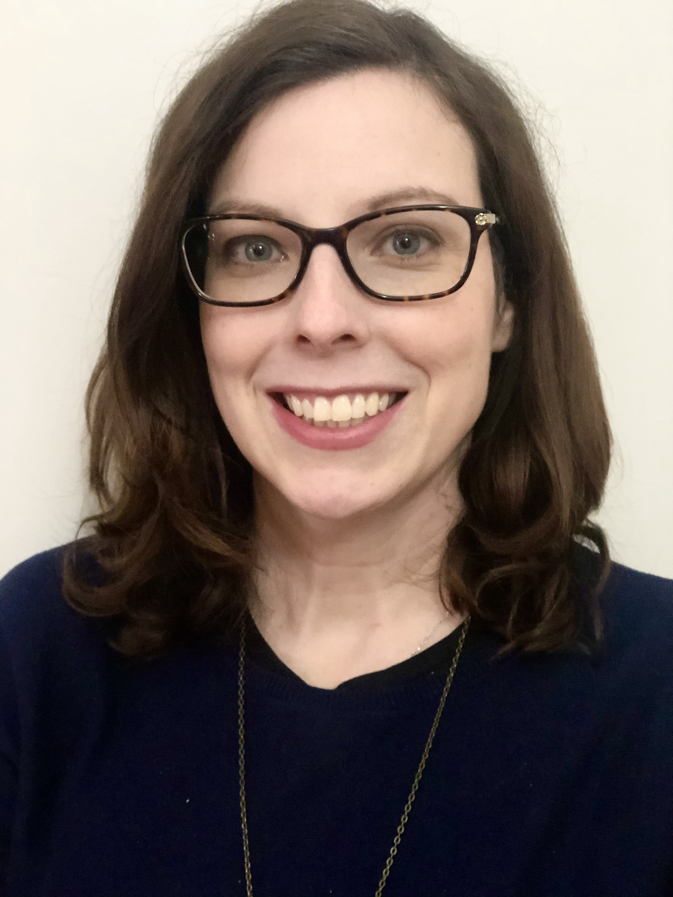 Kelly Dermody from the shoulders up wearing a dark coloured shirt, glasses and she is smiling.