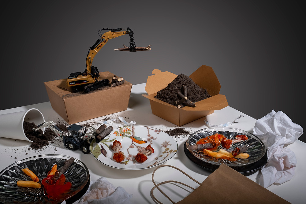 Toy construction vehicles moving dirt in the midst of a meal on top of a dining room table.