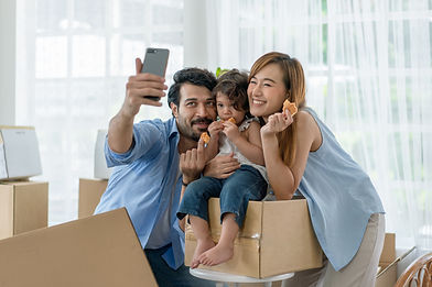 Two adults and a smill child posing for a selfie on top of moving boxes.