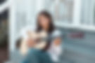 Musician Ella Klei playing guitar sitting on a front porch