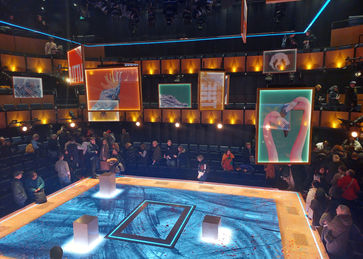 A theatre in the round. Picture frames hang from the grid, the stage floor also forming a giant picture frame around the story.