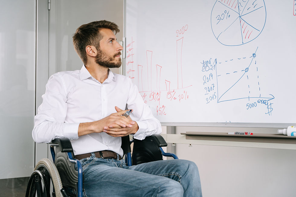 Young man in a wheelchair reviewing charts on a whiteboard, representing understanding what NDIS Short Term Accommodation involves.