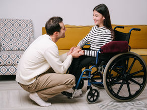 Man holds woman's hands, sharing a warm and supportive moment indoors.