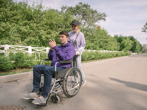 A happy couple enjoying a sunny day outdoors with a man in a wheelchair.
