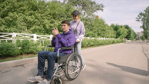 A happy couple enjoying a sunny day outdoors with a man in a wheelchair.