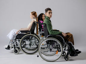 Three diverse individuals in wheelchairs posing indoors, symbolizing inclusivity.