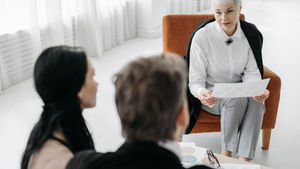 Professional advisor discussing documents with a couple in a modern office, reflecting an NDIS planning conversation with a Local Area Coordinator.