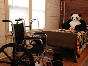 A warm bedroom featuring a wheelchair and soft furnishings, symbolising comfort and accessibility.