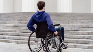 Participant in a wheelchair and support worker planning goals with a laptop and notes.
