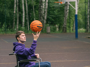 Young man in wheelchair at a basketball court representing active participation and high physical support capability.