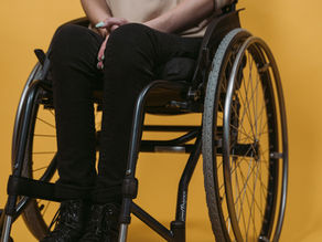 Participant in a wheelchair being supported outdoors, representing quality and safe support delivery.