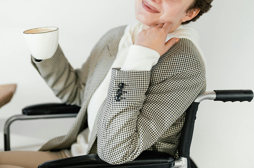 Woman in wheelchair holding a hot drink and smiling while spending time in a café.