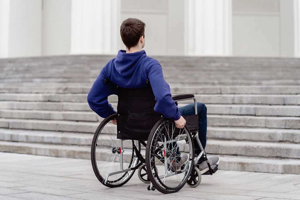 Participant in a wheelchair and support worker planning goals with a laptop and notes.