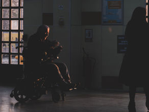 Silhouette of a person in a wheelchair inside a hospital corridor during sunset.
