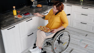 Woman using wheelchair prepares breakfast in kitchen, demonstrating independence during an NDIS STA stay.