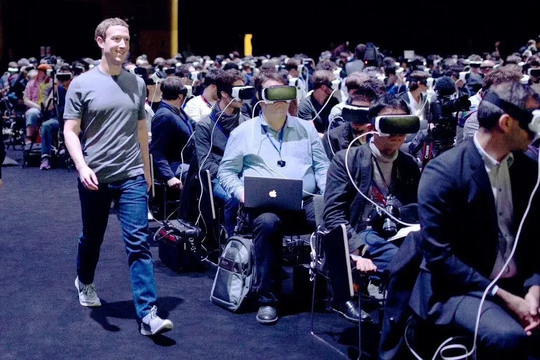 Fotografia che ritrae Mark Zuckerberg mentre attraversa una folla di persone con i visori e immerse nella realtà virtuale