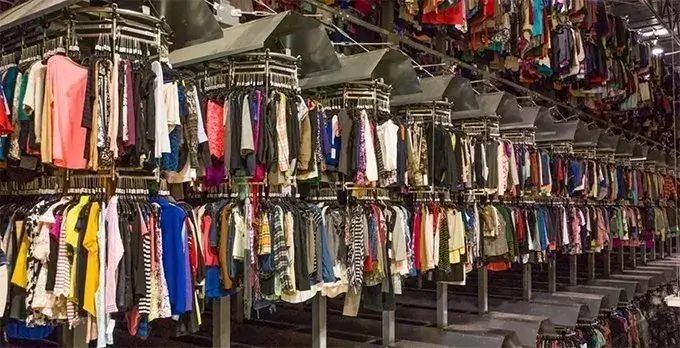 Un capannone pieno i vestiti appesi, rappresentante il sistema ormai sempre più comune del fast fashion
