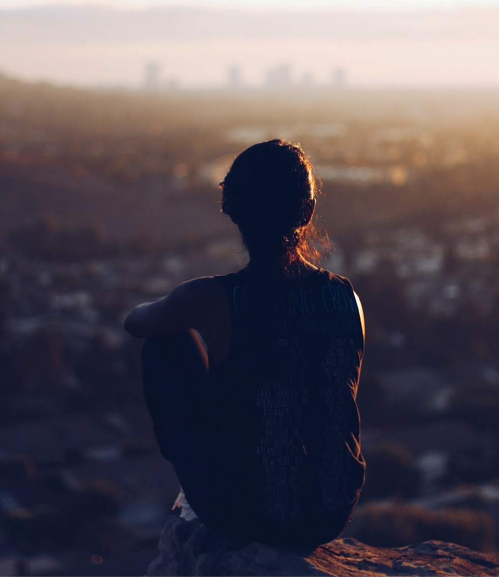 Silhouette of a person at sunset, with the sun casting a warm glow behind them.