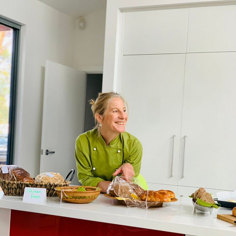 Anita leaning over her kitchen bench with a warm smile