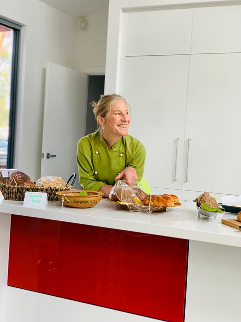 Anita leaning over her kitchen bench with a warm smile