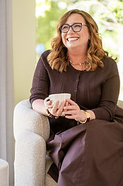 Valerie Timms smiling at camera - relaxed and holding a coffee