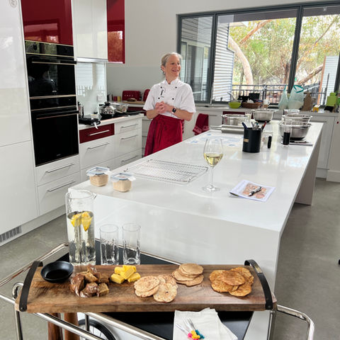 Anita in her kitchen wearing a red apron in her red and white kitchen