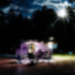 A trailer with camping chairs is lit under a starry sky and bright moon, surrounded by trees. The logo "pindrop Travel Trailers" is visible.