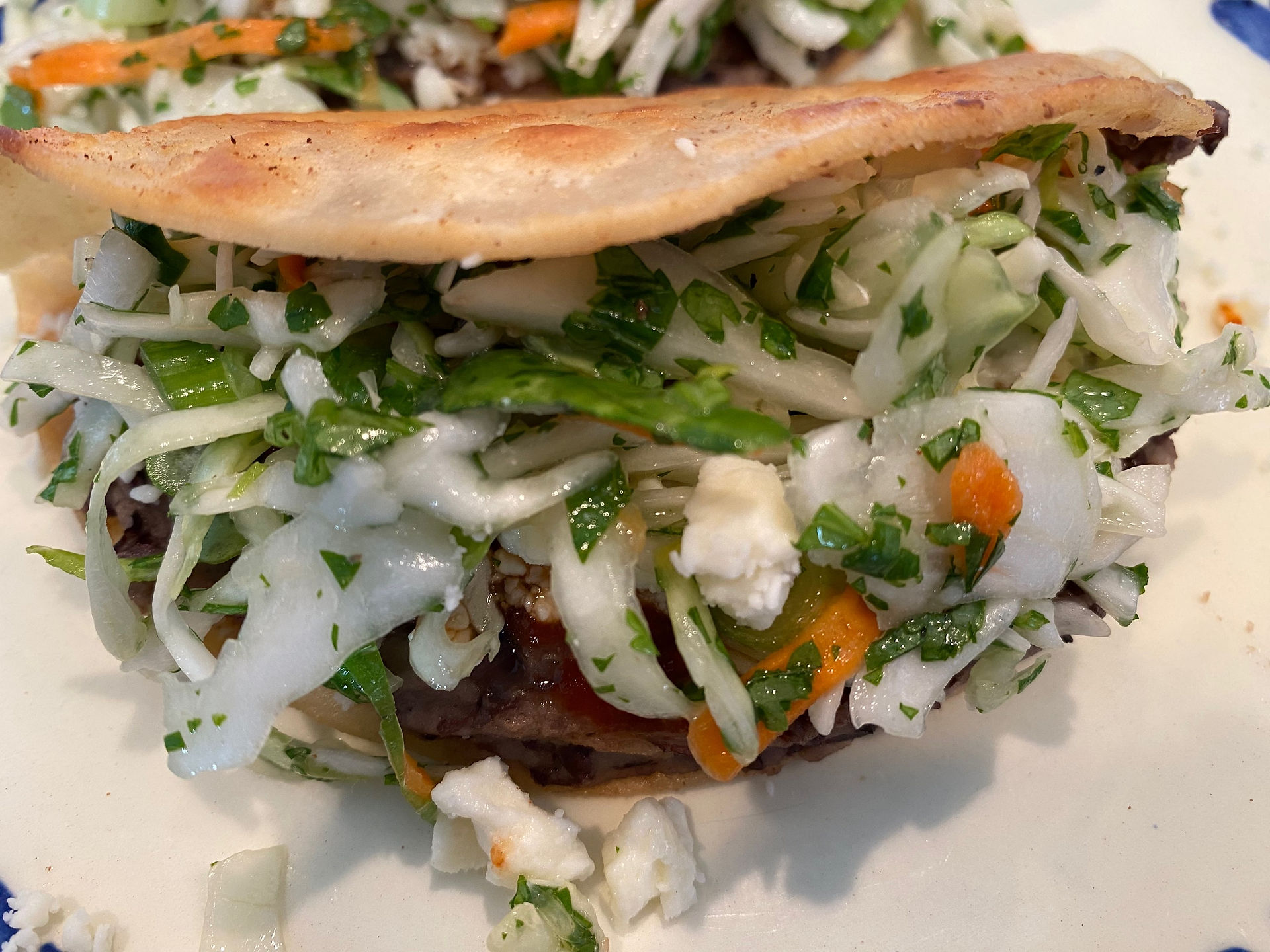 Ready to eat black bean taco with feta, hot sauce, and slaw