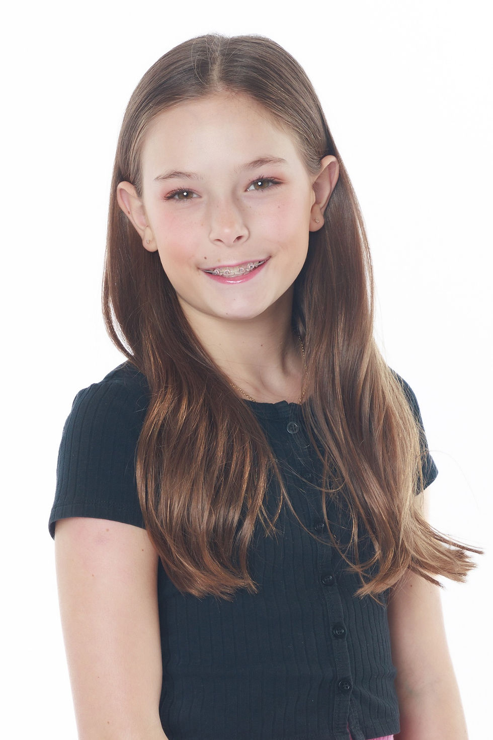 A headshot of a 9-11 year-old girl, smiling, with long, straight, dark blonde hair, wearing braces, and a blue shirt, against a white background.