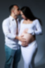 Couple posing together during a maternity photoshoot at Tals Studio in NYC, surrounded by soft studio lighting and neutral backdrops.
