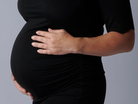 Pregnant woman posing during a professional maternity photoshoot in NYC at Tals Studio
