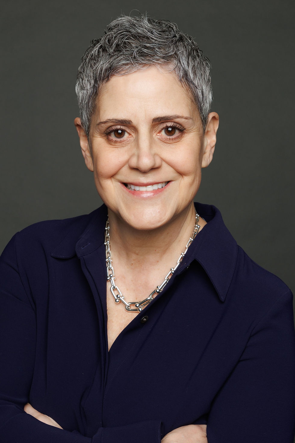 Headshot of a man wearing a suit, tie, and smiling, with a white background.