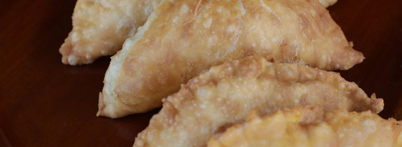 Golden fried empanadas arranged on a rectangular serving plate