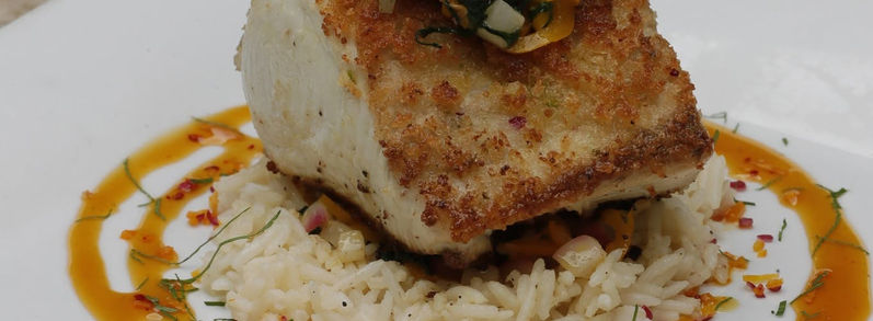Pan-seared sea bass served with rice, vegetables and orange sauce