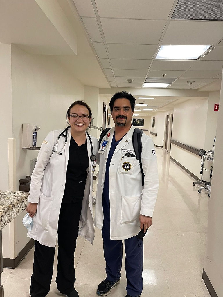 Médicos sonriendo en pasillo hospitalario, cuidando a nuestros pacientes.